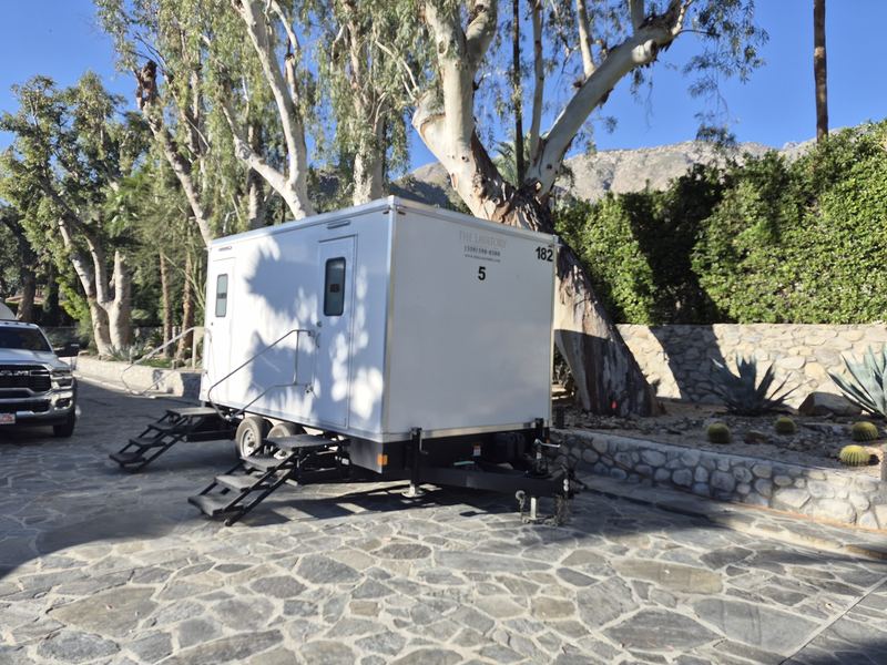 Large multi-stall restroom trailer on a stone patio