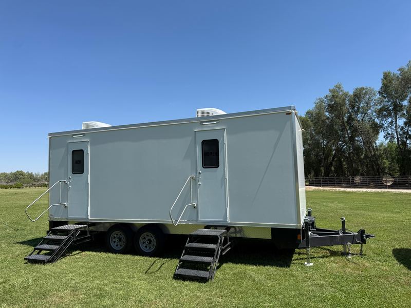 Long restroom trailer on a green lawn ready for an event