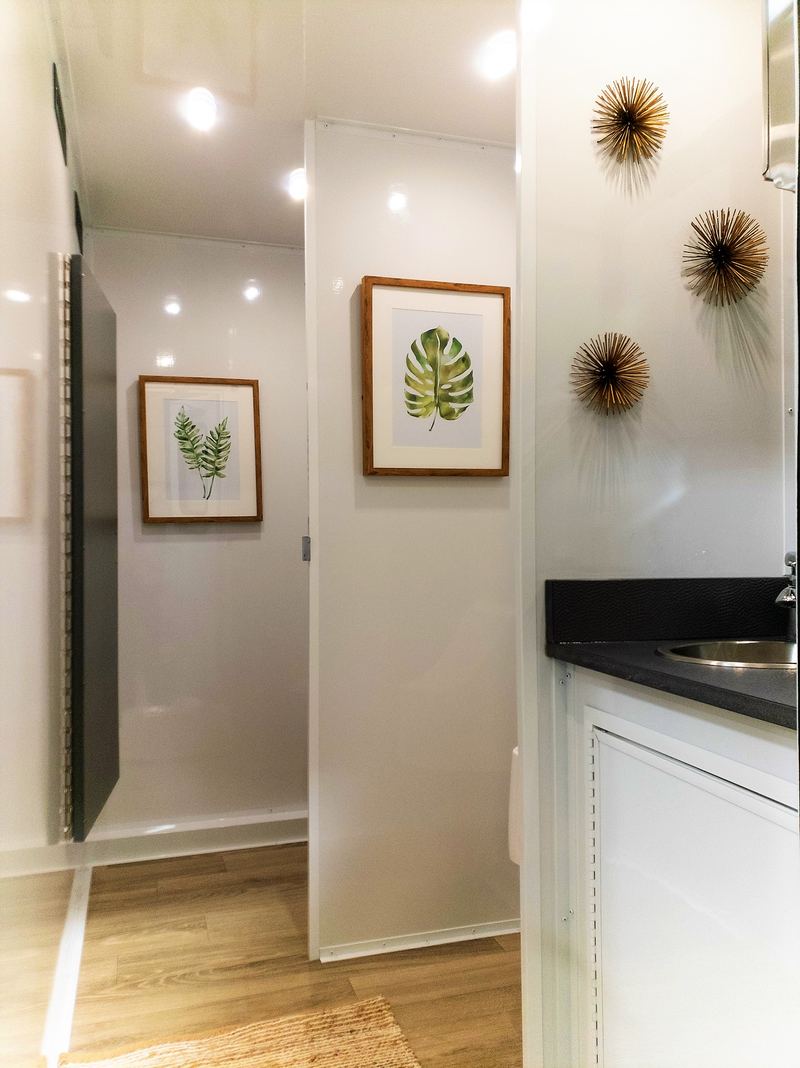 Bright hallway inside a restroom trailer with wall art and a vanity