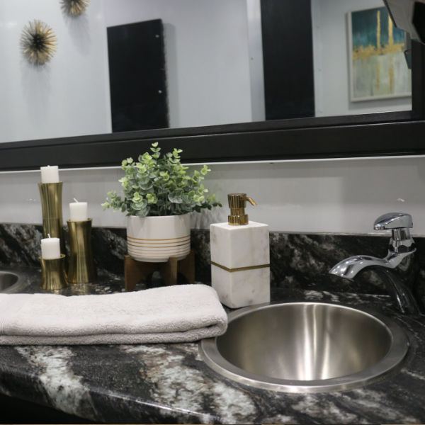 Countertop vanity with a steel sink and towels in a restroom trailer